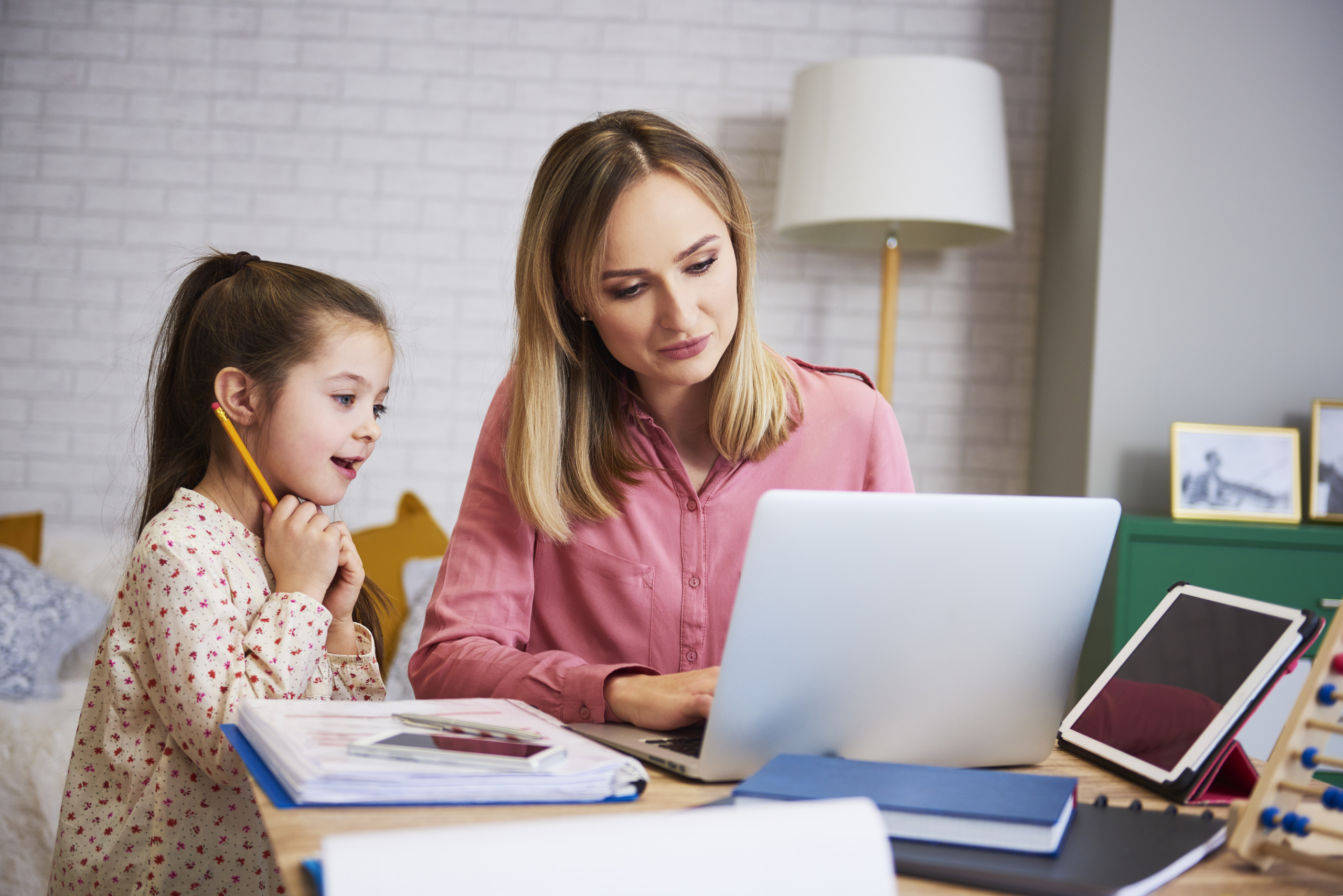 Erwachsene Frau zeigt Kind etwas auf Laptop